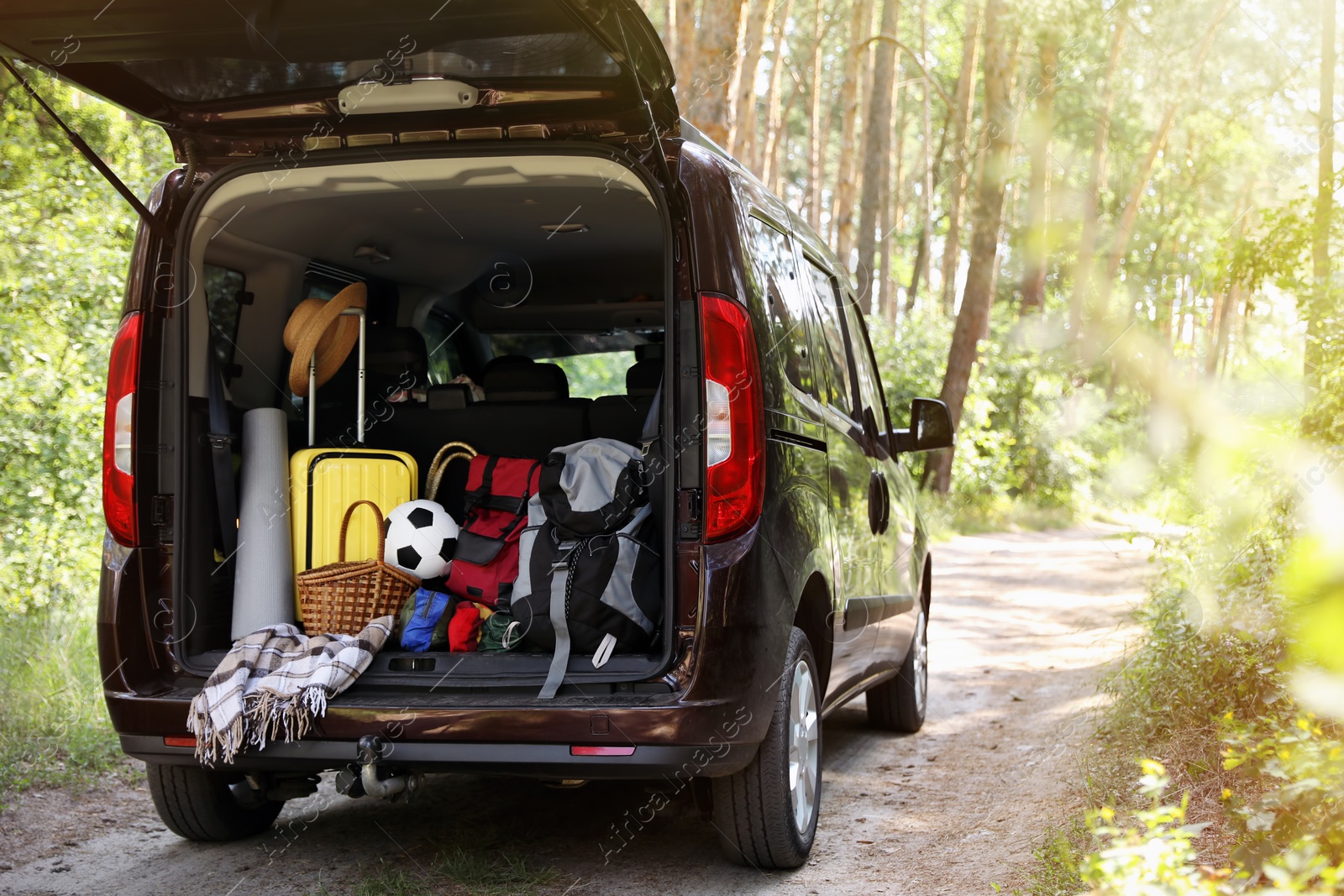 Photo of Van with camping equipment in trunk outdoors