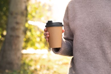 Photo of Coffee to go. Woman holding takeaway cardboard cup on city street, closeup. Space for text