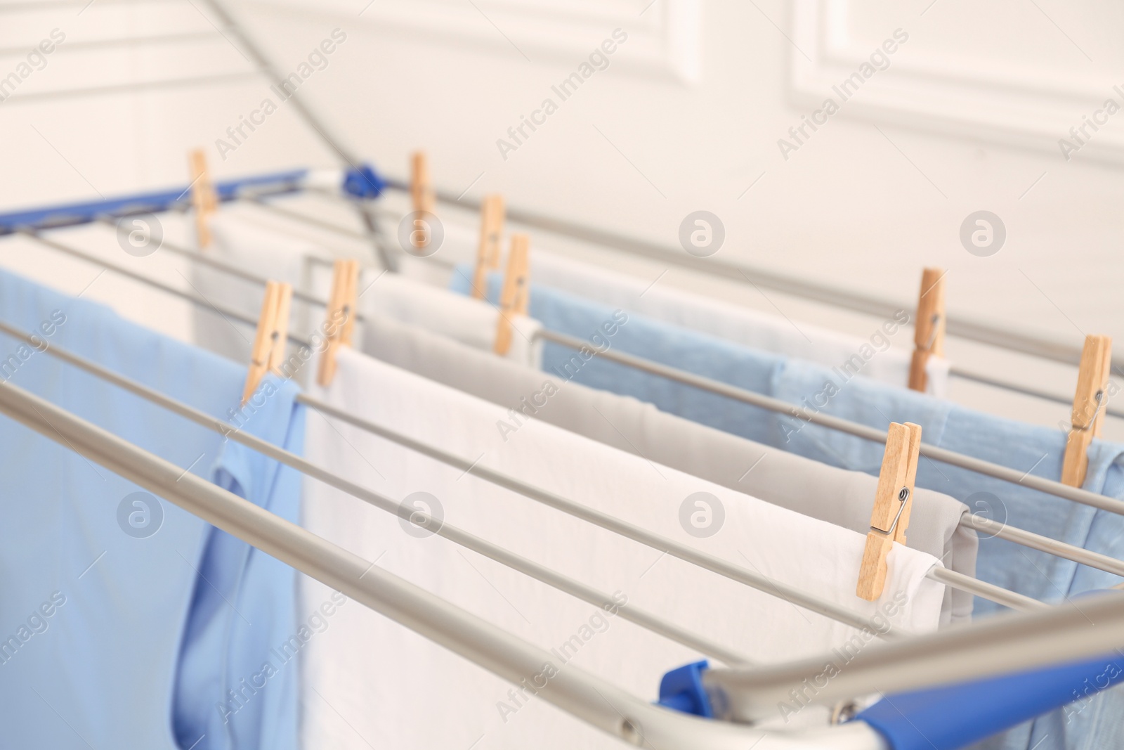 Photo of Clean laundry hanging on drying rack indoors, closeup