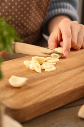 Photo of Woman cutting fresh garlic at table, closeup