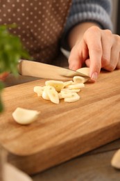 Woman cutting fresh garlic at table, closeup