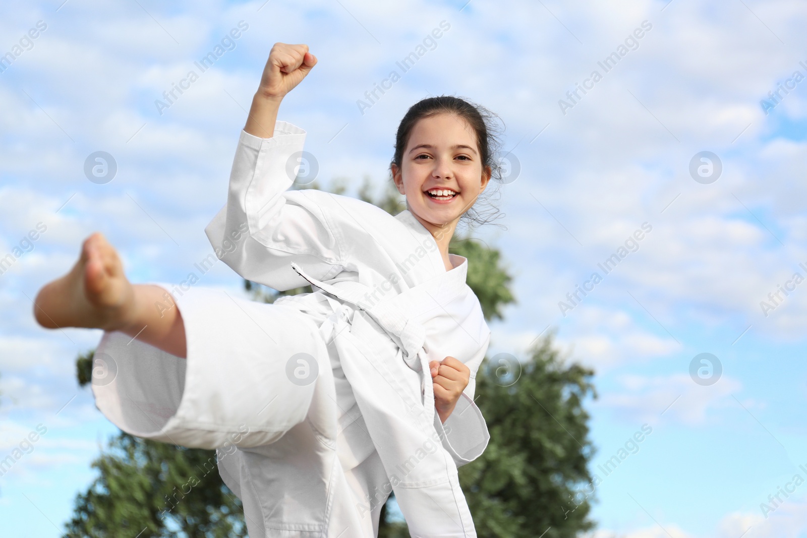 Photo of Cute little girl in kimono training karate outdoors