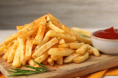 Photo of Delicious french fries served with sauce on wooden board, closeup