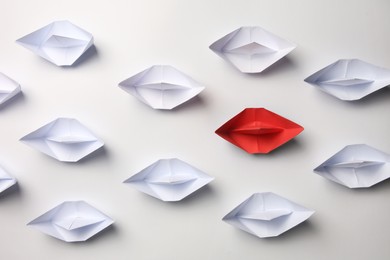 Photo of Red paper boat among others on white background, flat lay. Uniqueness concept