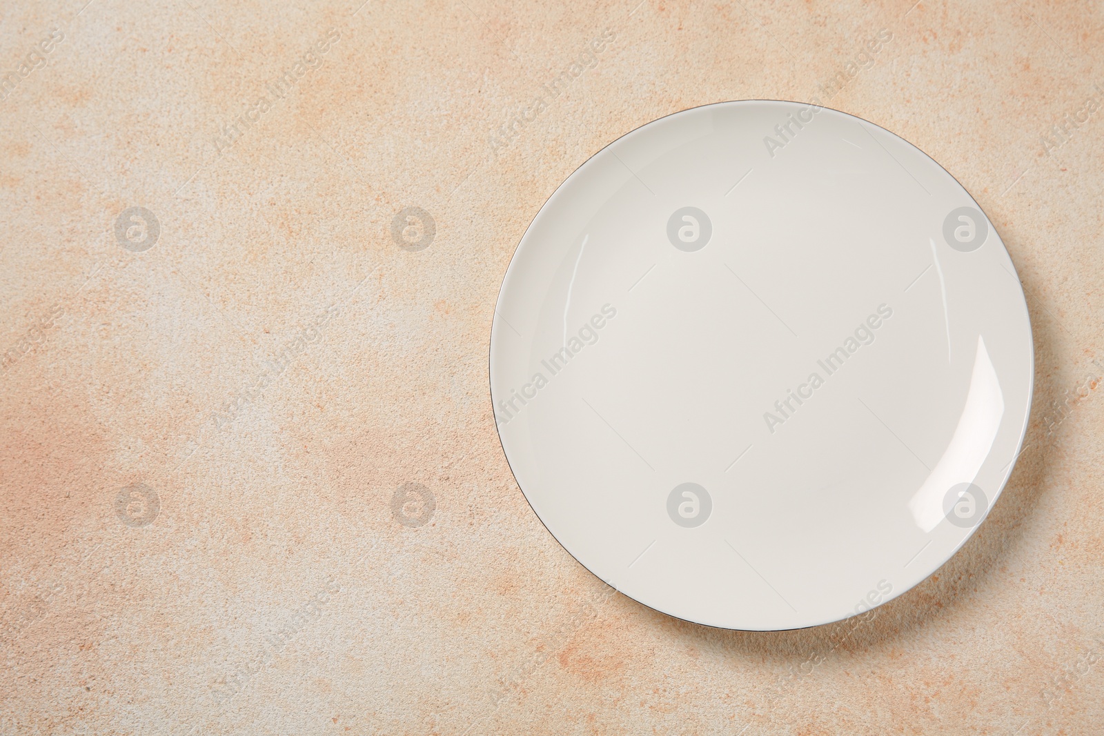 Photo of One ceramic plate on beige table, top view. Space for text