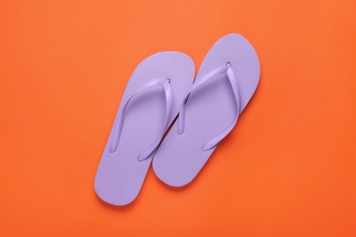 Photo of Stylish violet flip flops on orange background, top view