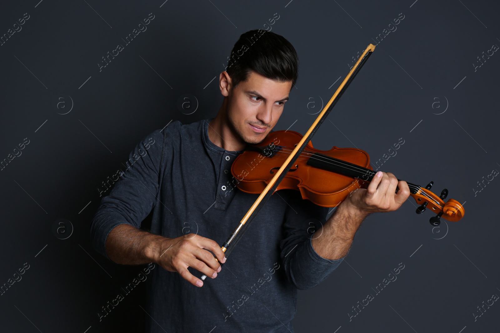 Photo of Man playing wooden violin on black background