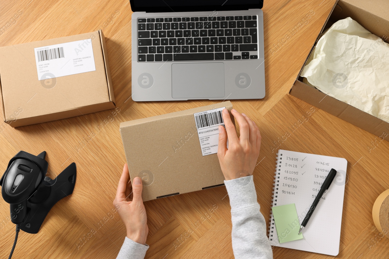 Photo of Woman with parcel at wooden table, top view. Online store