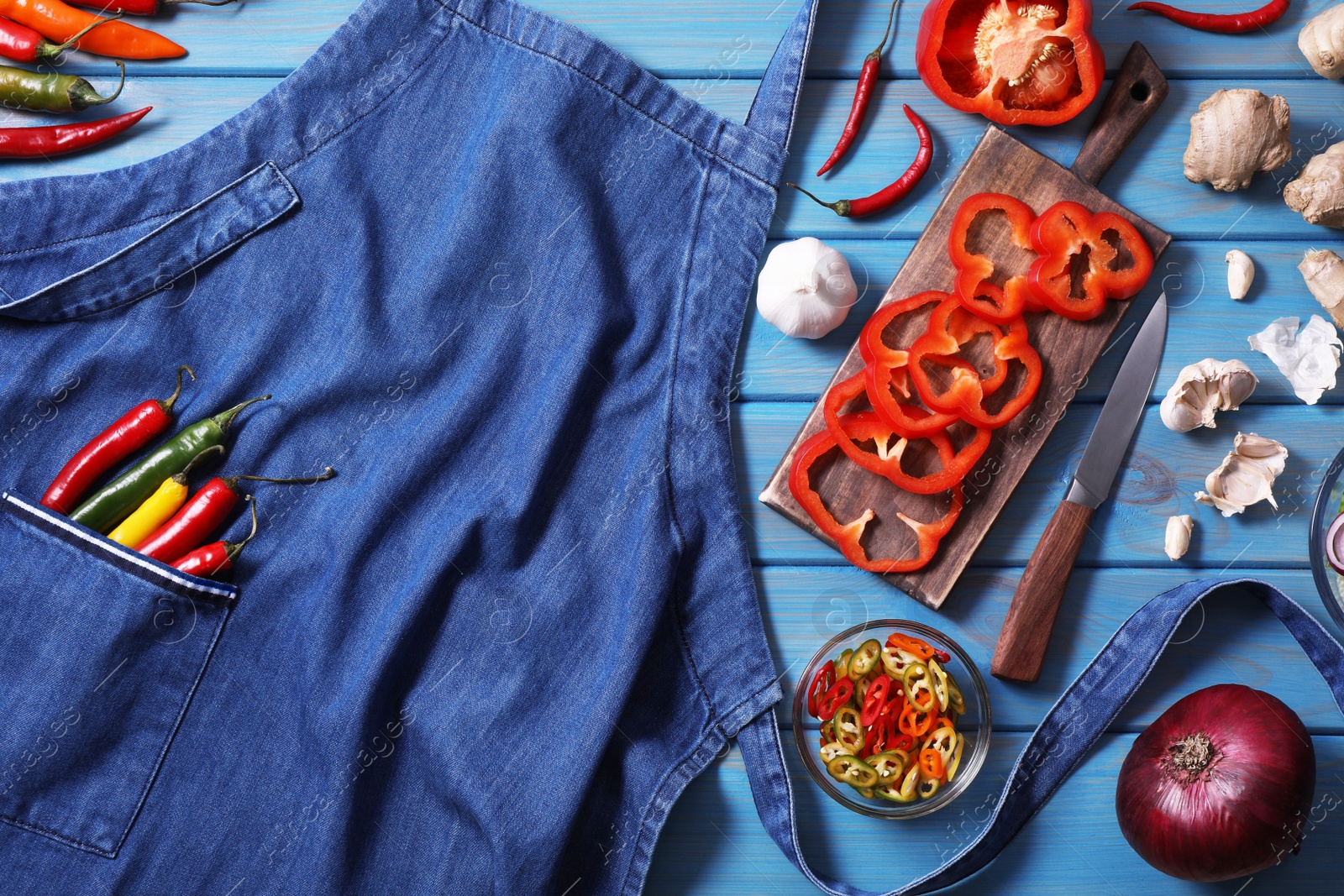 Photo of Flat lay composition with denim apron and different ingredients on light blue wooden table