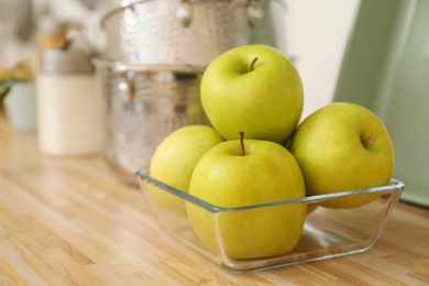 Apples in fruit bowl on wooden countertop in kitchen. Interior element