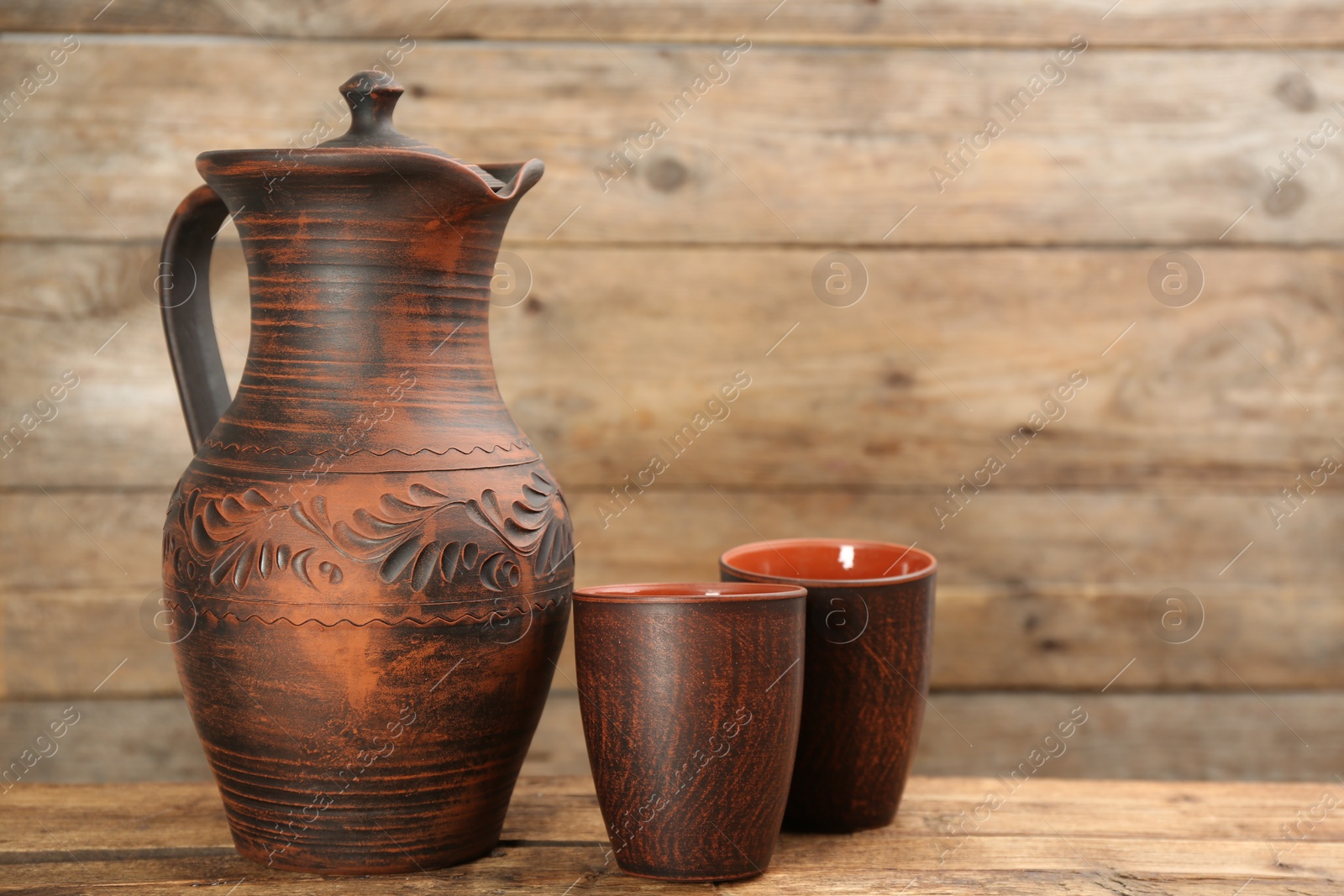 Photo of Clay jug and cups on wooden table