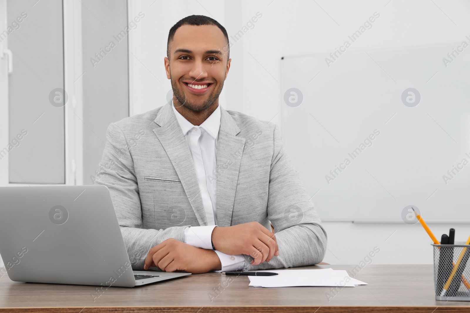 Photo of Happy young intern working at table in modern office