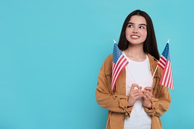 4th of July - Independence Day of USA. Happy girl with American flags on light blue background, space for text