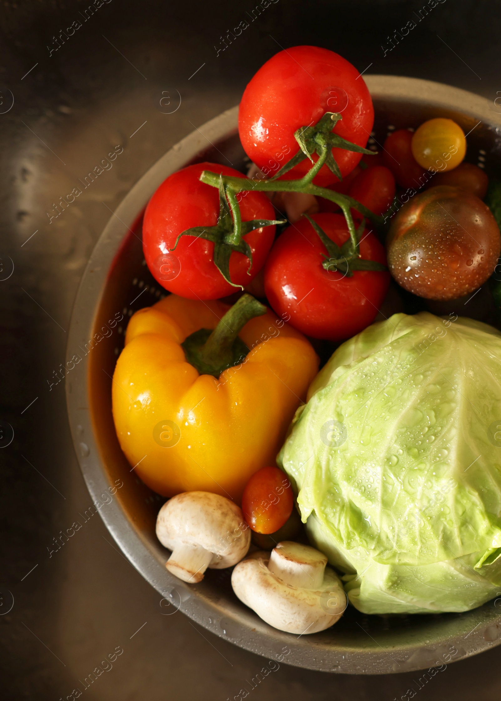 Photo of Different wet vegetables in metal colander inside sink, top view