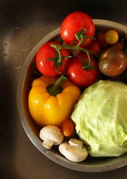 Photo of Different wet vegetables in metal colander inside sink, top view