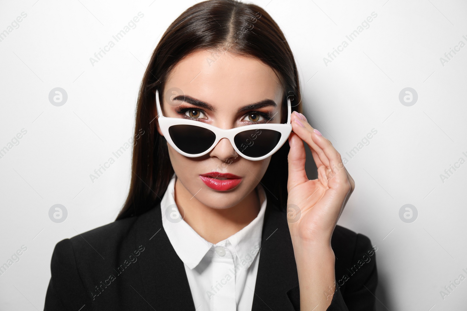 Photo of Young businesswoman in stylish sunglasses on light background