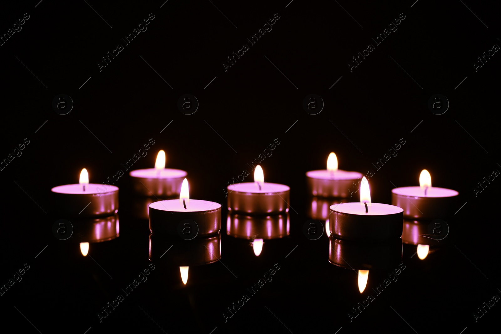 Image of Beautiful burning violet candles on black background. Funeral attributes