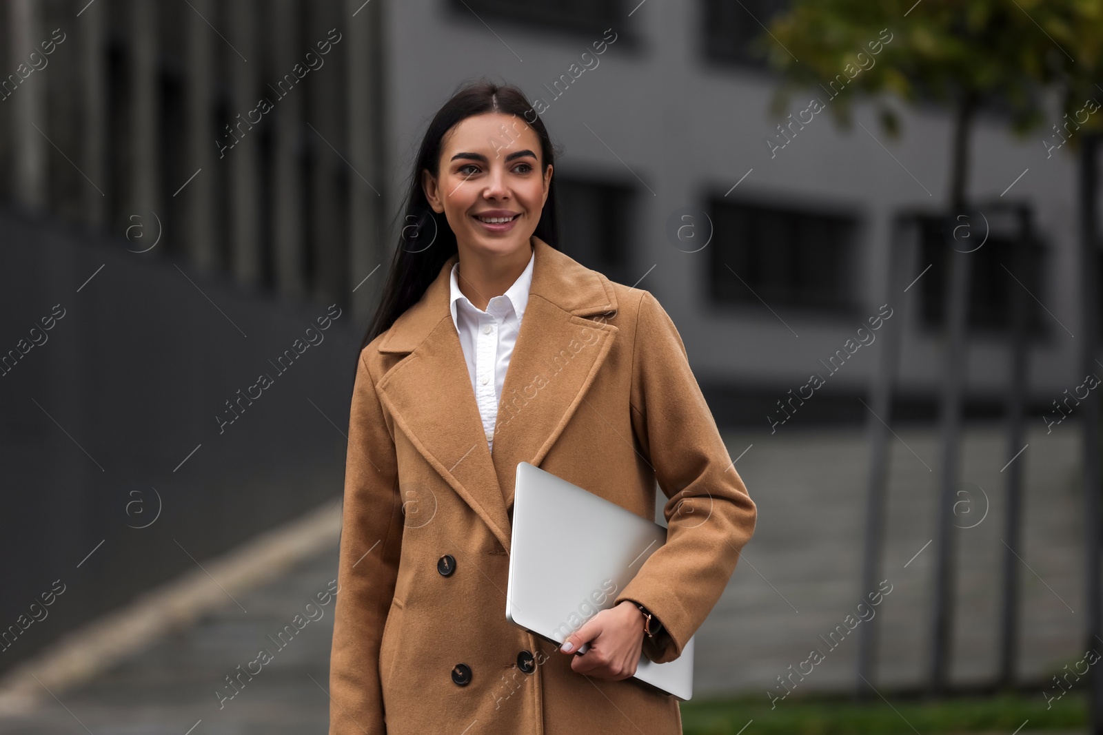 Photo of Smiling woman with laptop outdoors. Lawyer, businesswoman, accountant or manager