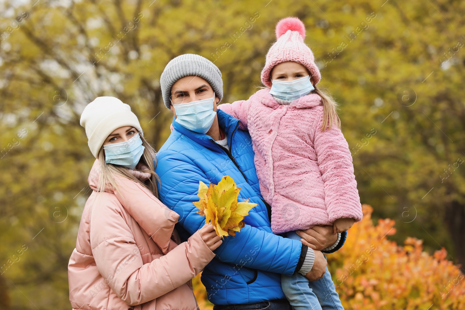 Photo of Family in medical masks outdoors on autumn day. Protective measures during coronavirus quarantine