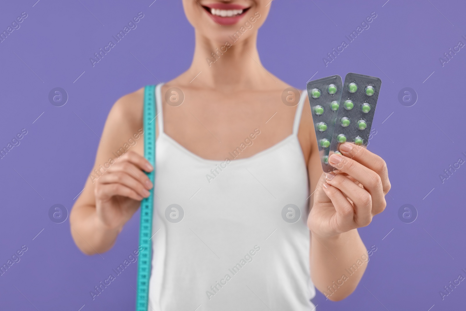 Photo of Woman with pills and measuring tape on purple background, closeup. Weight loss