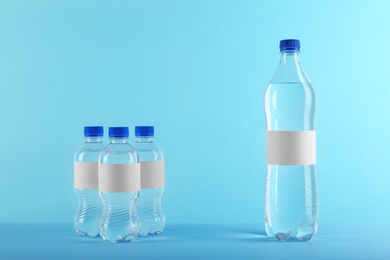 Different bottles of pure water with blank tags on color background