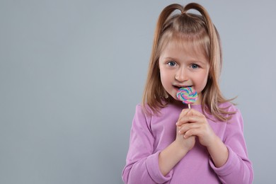 Photo of Portrait of cute girl with lollipop on light grey background. Space for text