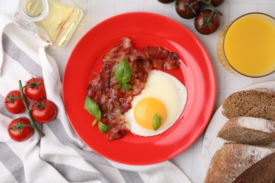 Fried egg and bacon served on white tiled table, top view