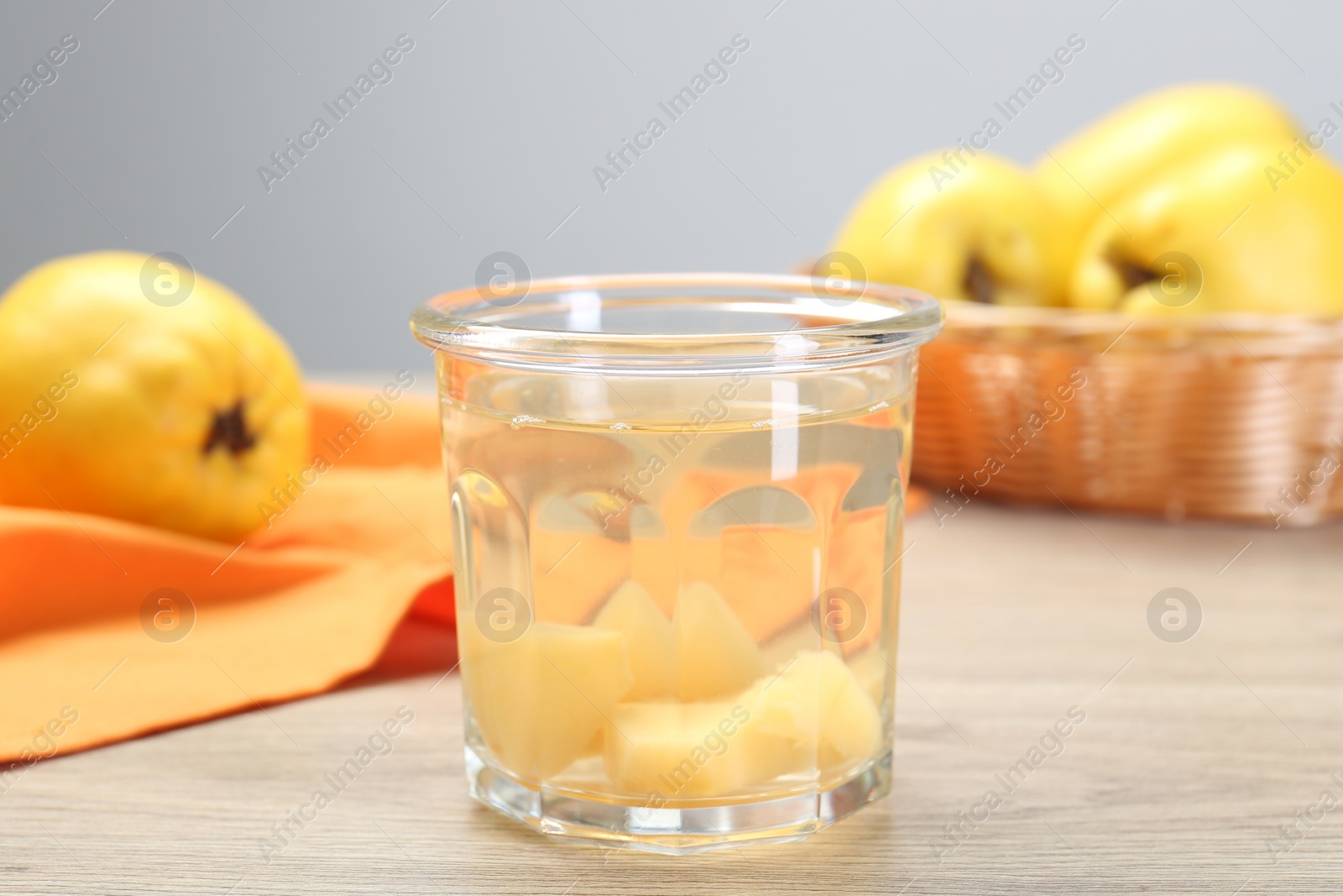 Photo of Delicious quince drink in glass and fresh fruits on wooden table, closeup