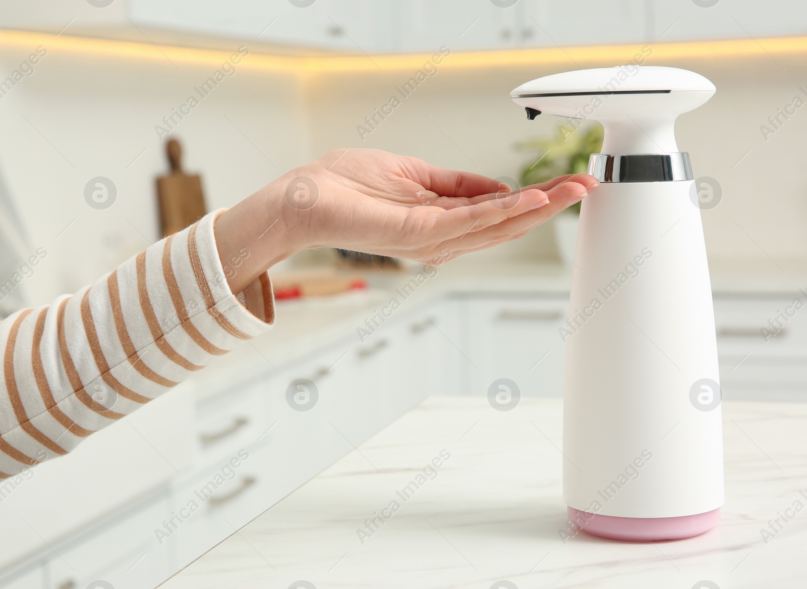 Photo of Woman using automatic soap dispenser in kitchen, closeup