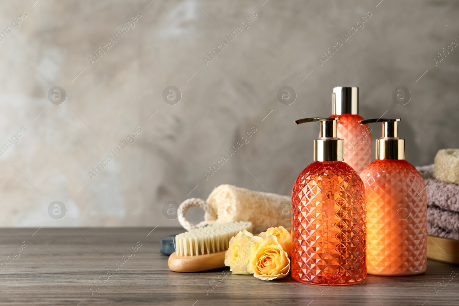 Photo of Stylish dispensers with liquid soap and other bathroom amenities on wooden table, space for text