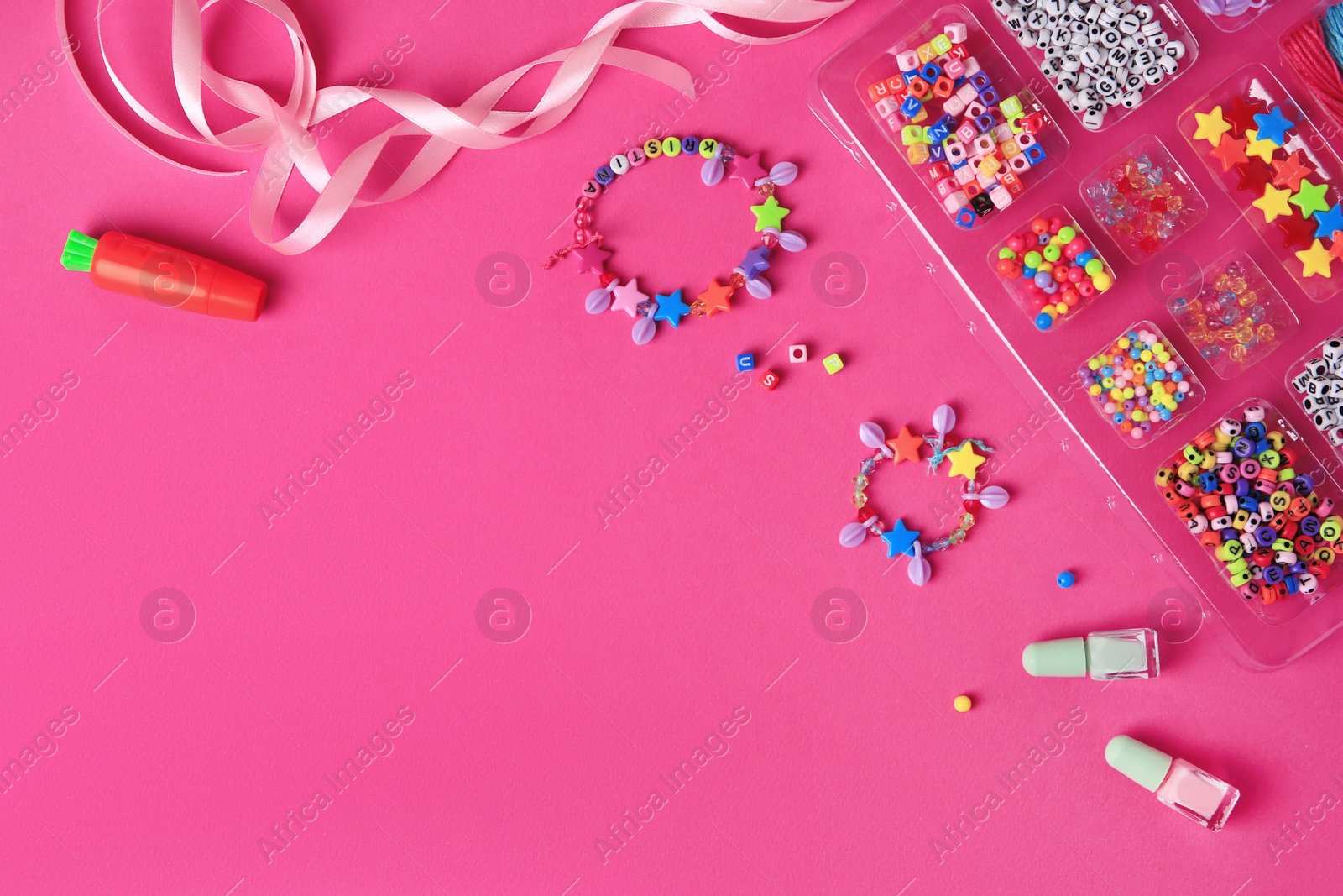 Photo of Handmade jewelry kit for kids. Colorful beads, ribbon and bracelets on bright pink background, flat lay. Space for text