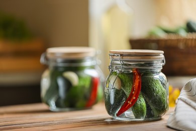 Jar of pickled cucumbers on wooden table. Space for text