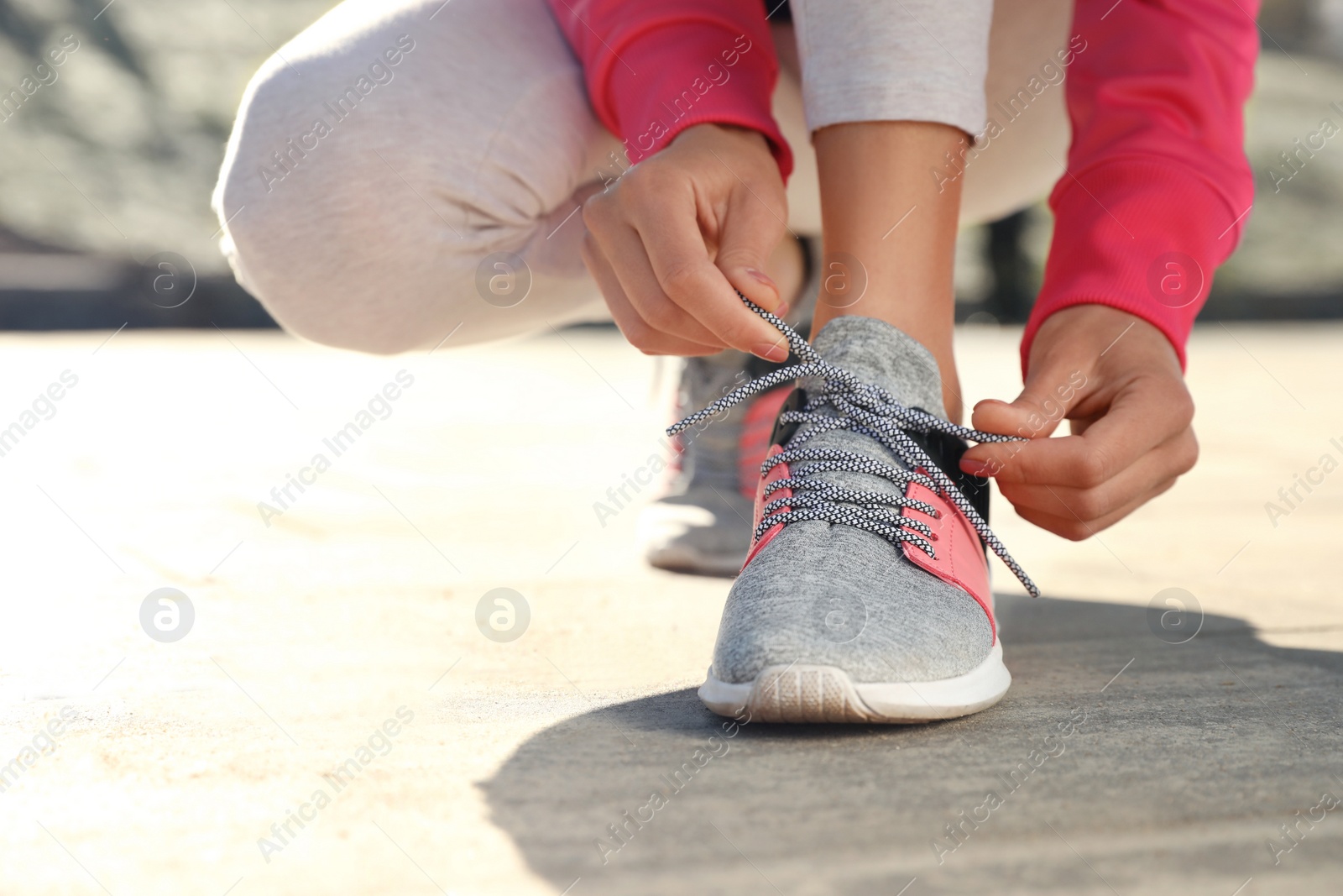 Photo of Sporty woman tying shoelaces before running outdoors