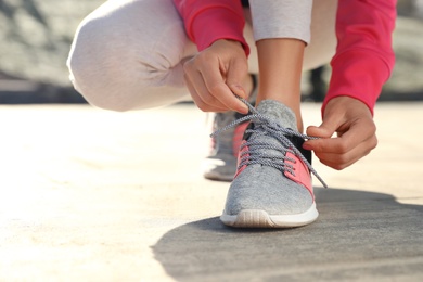 Sporty woman tying shoelaces before running outdoors