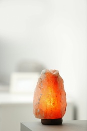 Himalayan salt lamp on table indoors, space for text