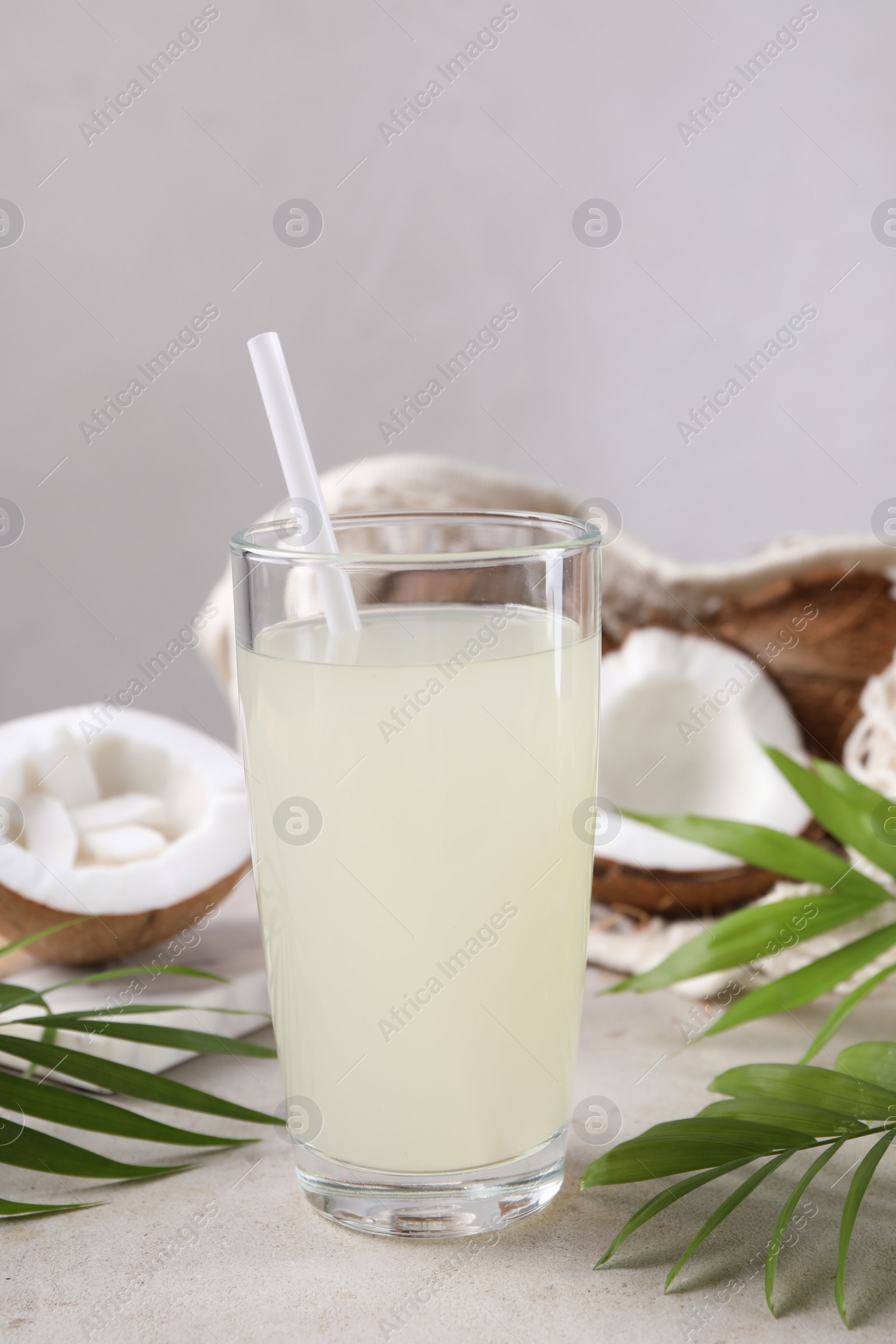 Photo of Glass of coconut water, palm leaves and nuts on light table