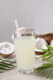 Photo of Glass of coconut water, palm leaves and nuts on light table