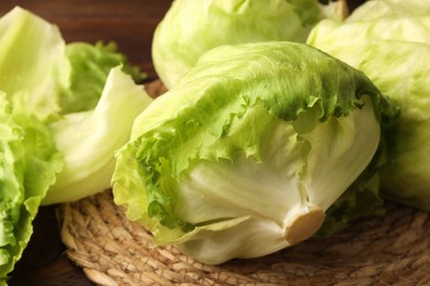 Photo of Fresh green iceberg lettuce heads and leaves on wicker mat, closeup