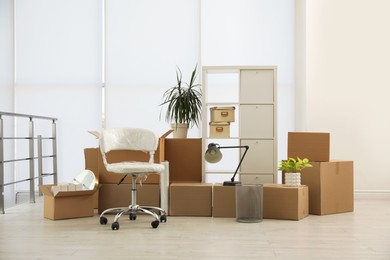 Photo of Cardboard boxes with packed stuff in new office. Moving day