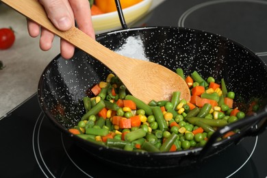 Photo of Woman cooking tasty vegetable mix in wok pan at home, closeup