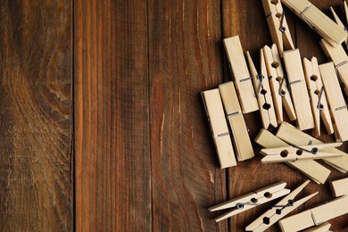 Photo of Pile of clothespins on wooden table, flat lay. Space for text