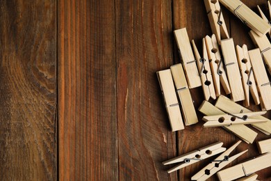 Pile of clothespins on wooden table, flat lay. Space for text