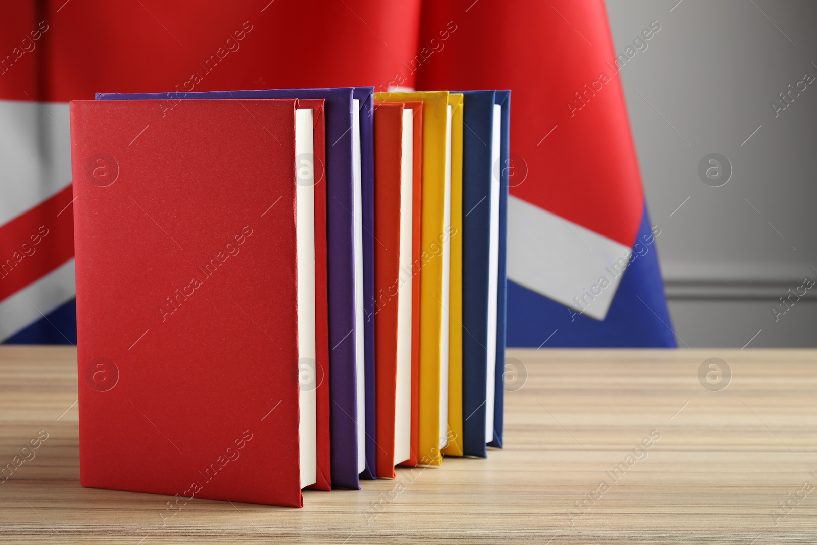 Photo of Learning foreign language. Different books on wooden table near flag of United Kingdom, space for text