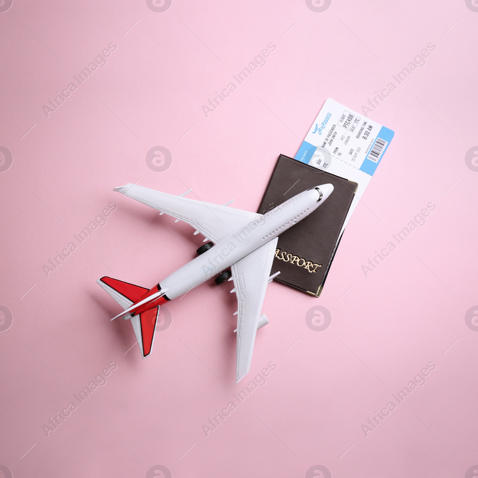 Photo of Toy airplane and passport with ticket on pink background, flat lay