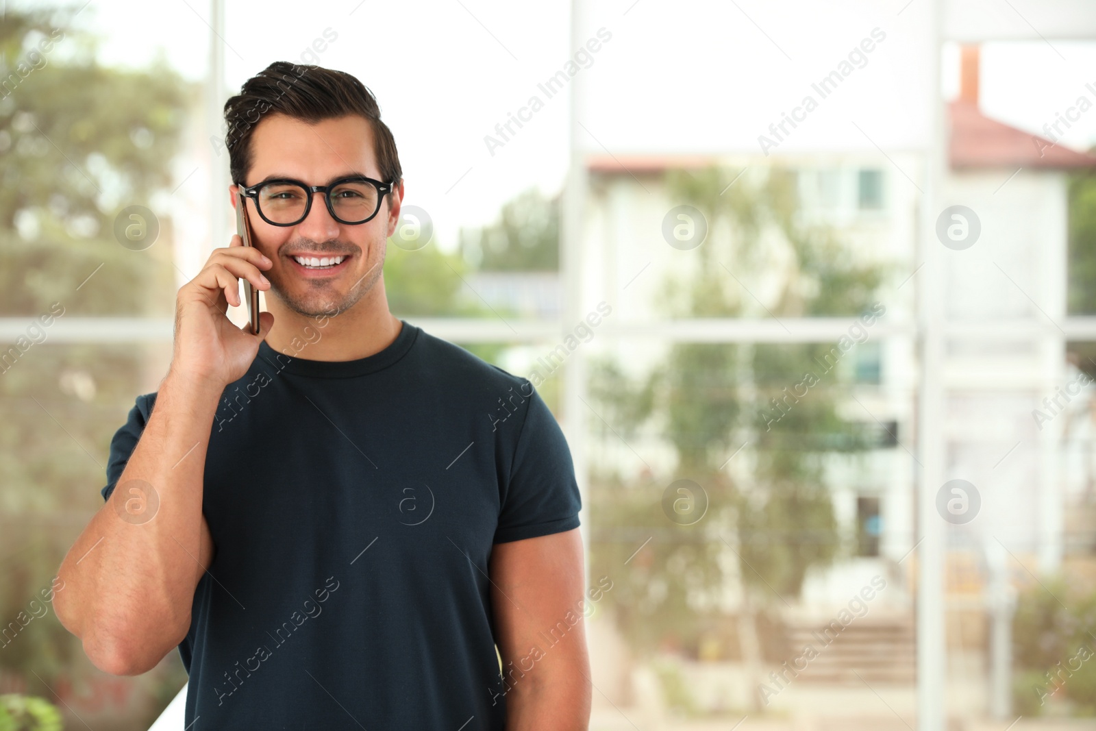 Photo of Portrait of handsome young man talking on phone indoors. Space for text