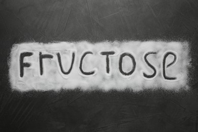 Photo of Word Fructose made of sugar on black table, top view