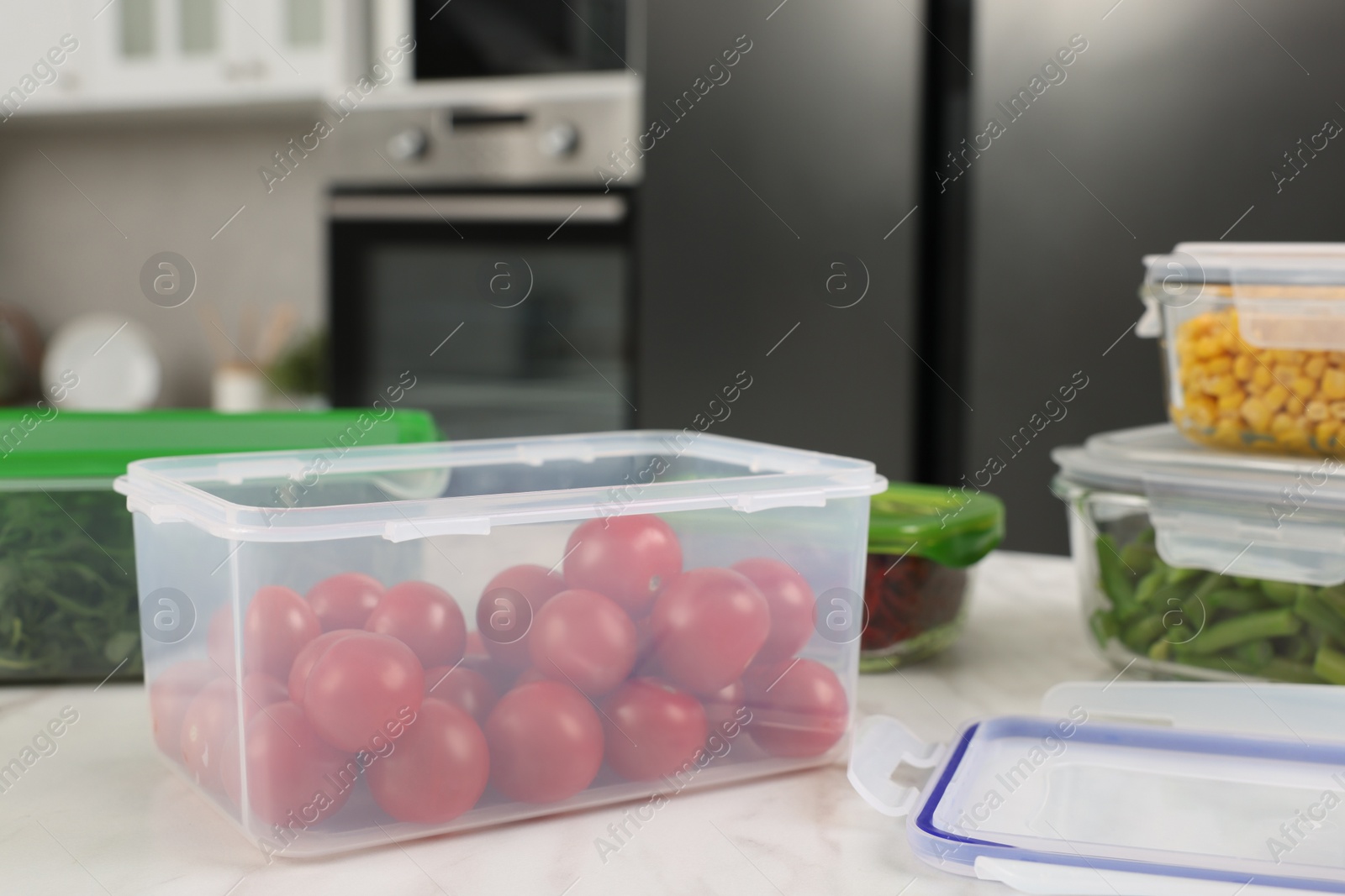 Photo of Plastic and glass containers with different fresh products on white marble table in kitchen. Food storage