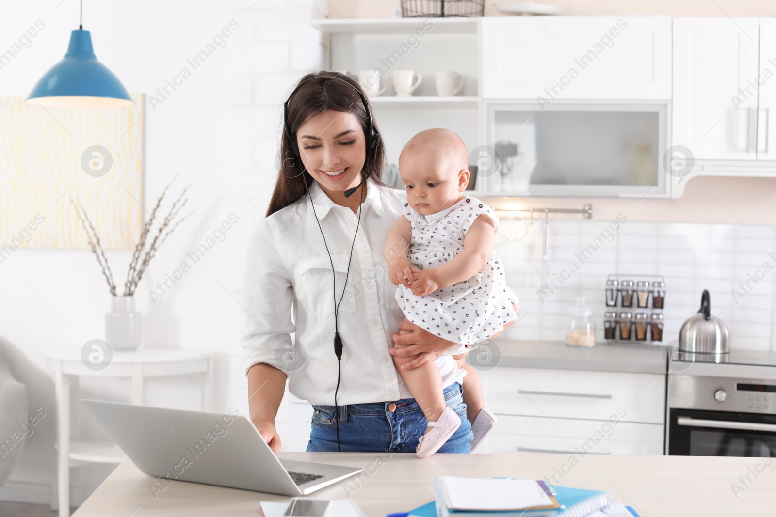 Photo of Young mother with her cute baby girl working at home