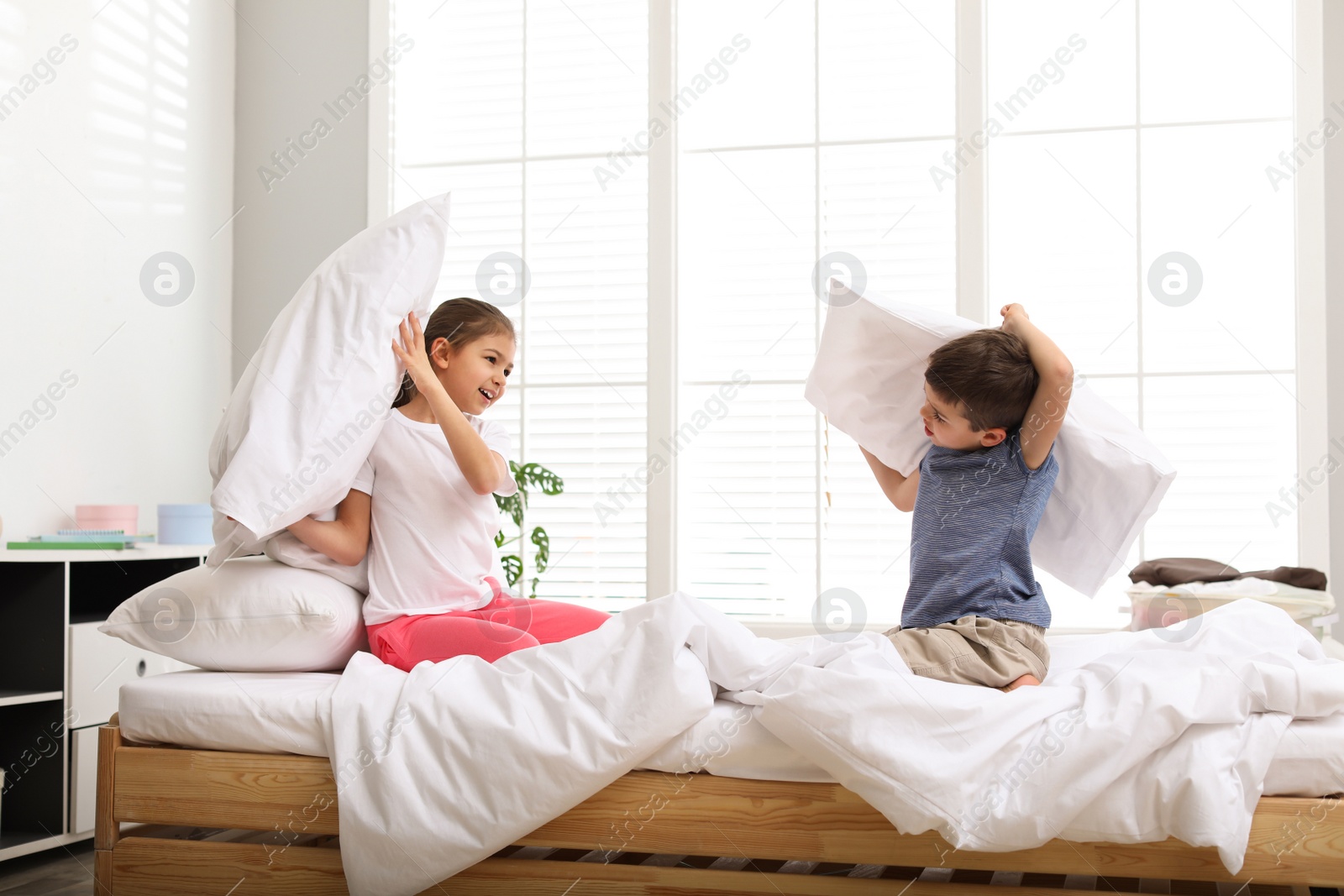 Photo of Happy children having pillow fight in bedroom