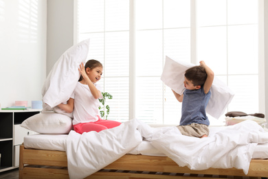 Happy children having pillow fight in bedroom